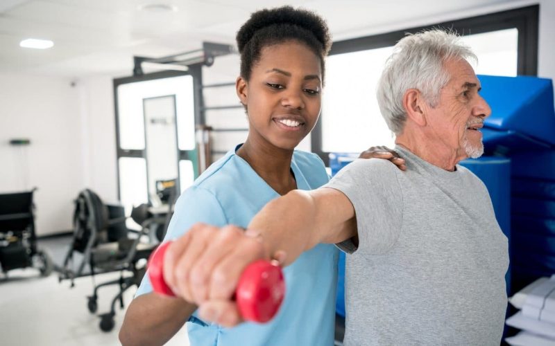 African american occupational therapist helping a senior patient with his shoulder workout
